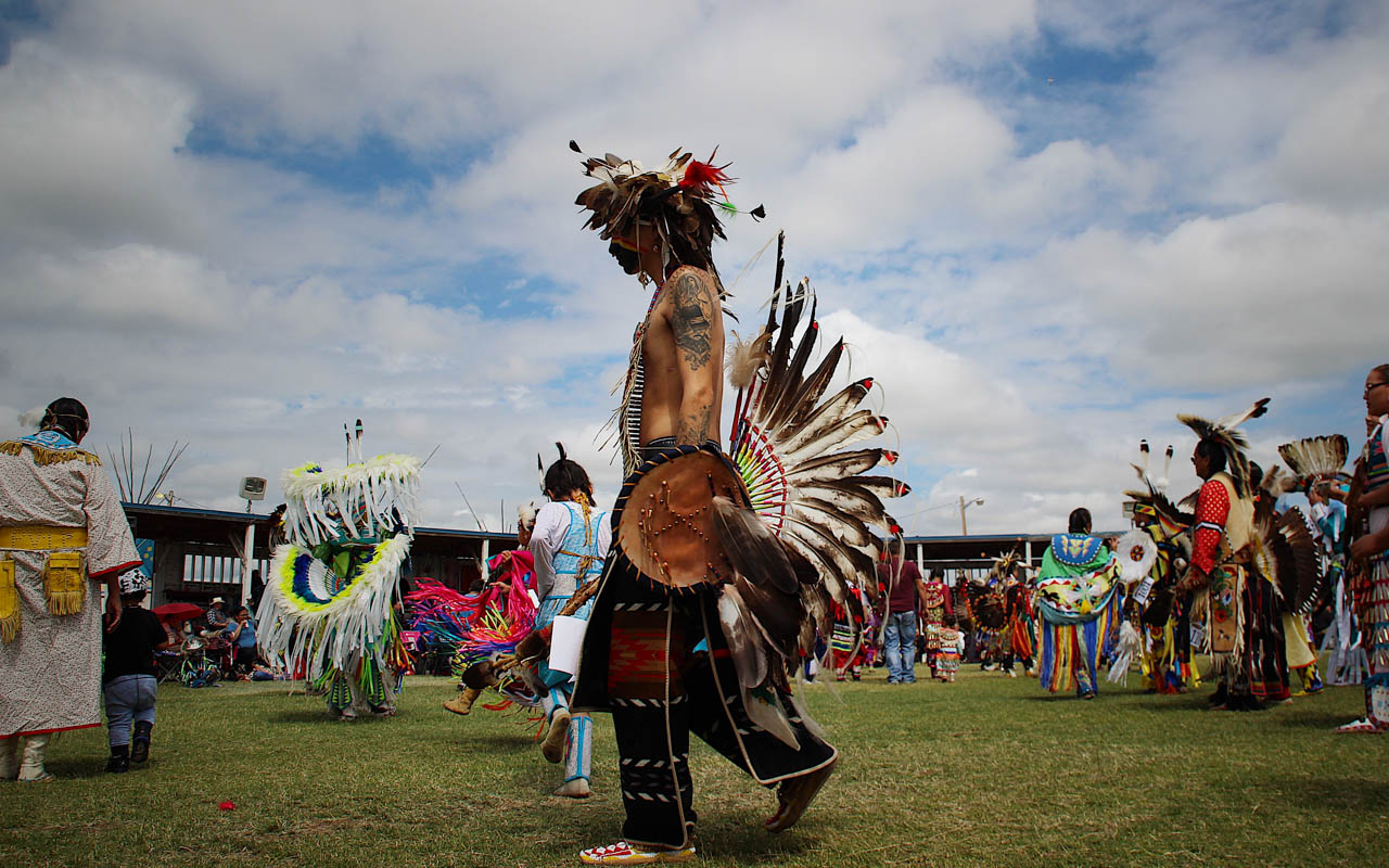 A Blackfeet Native American man walking in full native dress at a powwow
