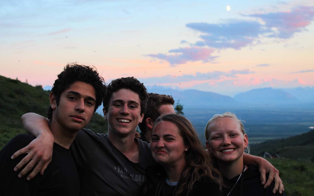 Teens on a hike in Alaska smiling at sunset