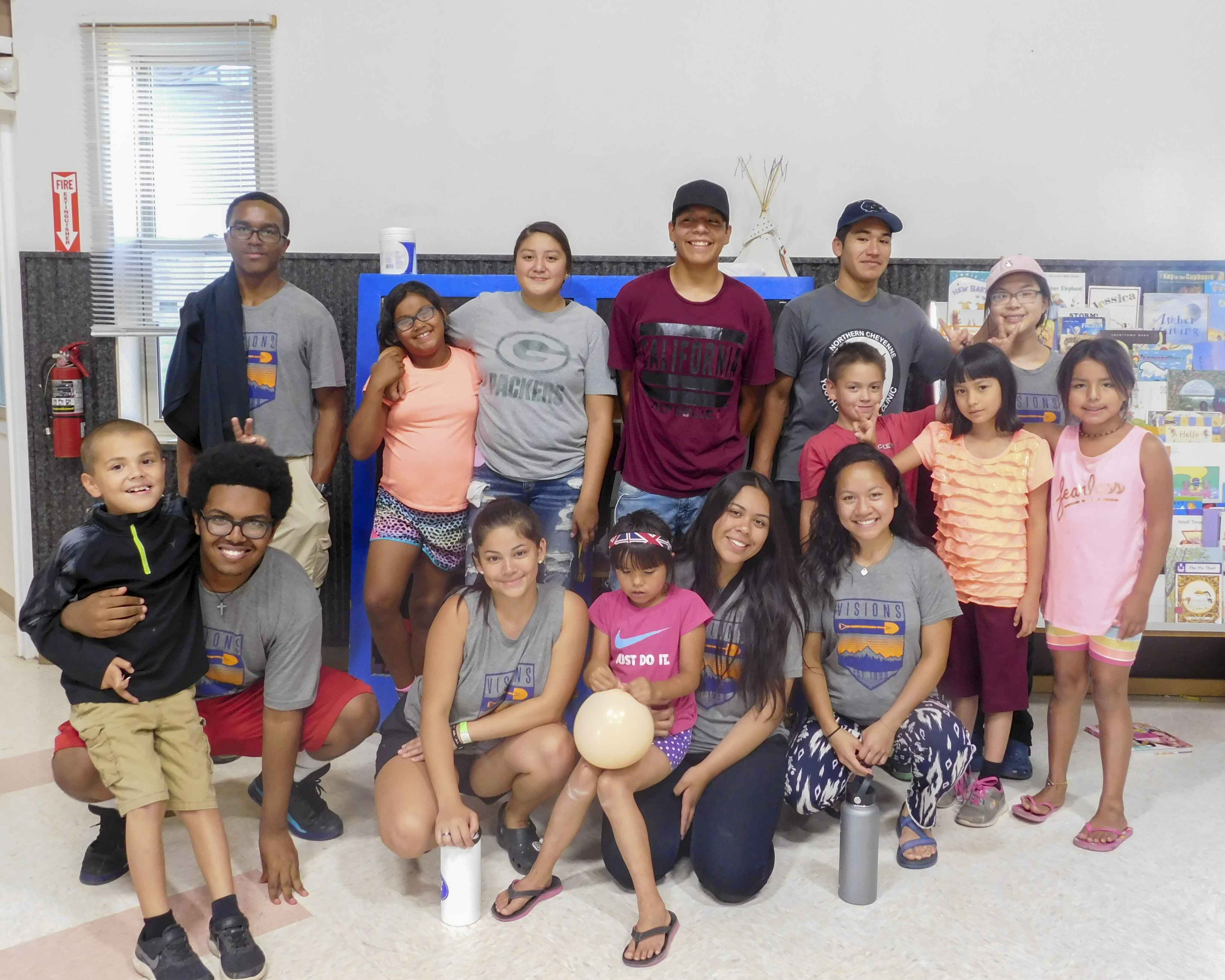 Teen volunteers stand with local community members and children at day camp on community service trips to the Northern Cheyenne