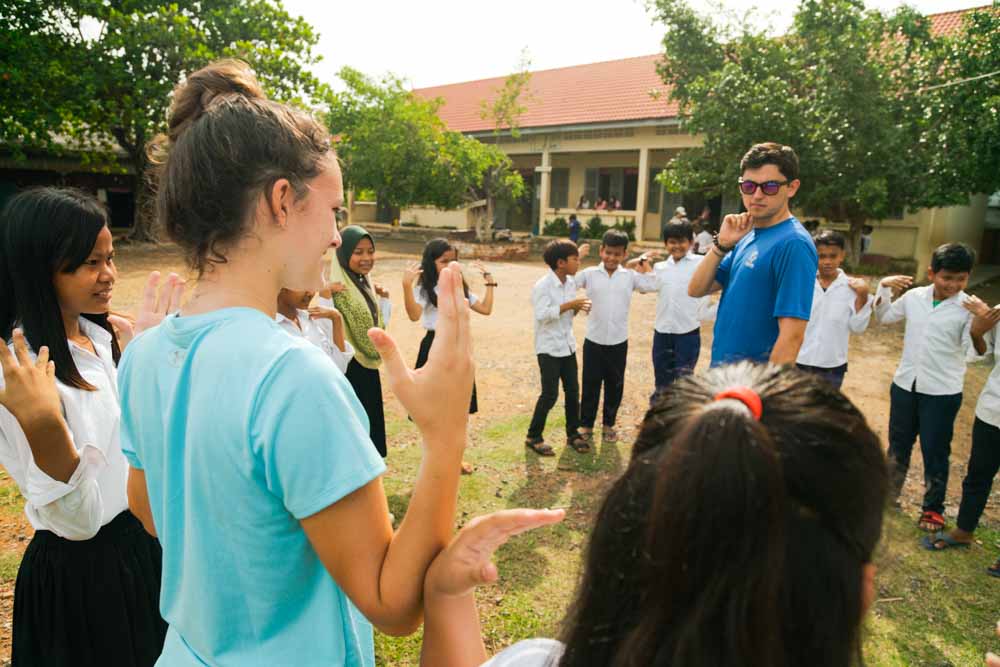 Teens play games with school children in Cambodia.