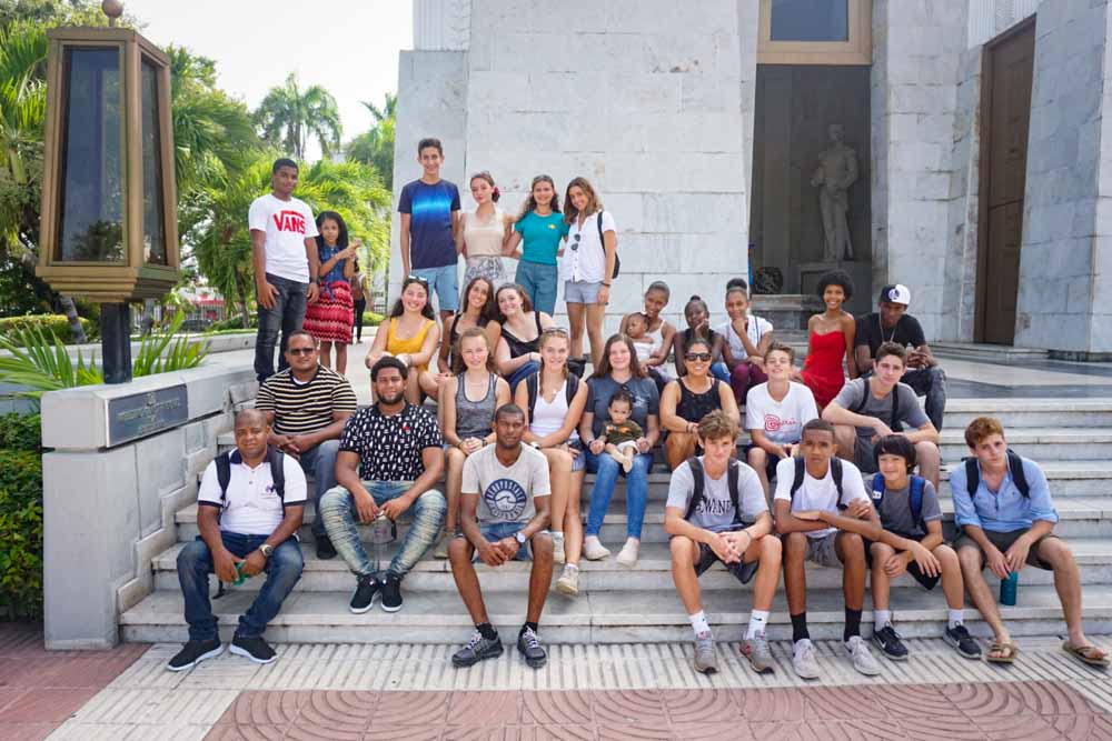 Teen volunteers and program leaders pose on some steps for a group photo in the Dominican Republic.