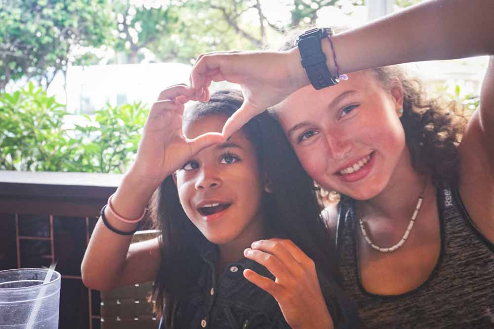 A teen volunteer and local child make a heart with their hands in the Dominican Republic.