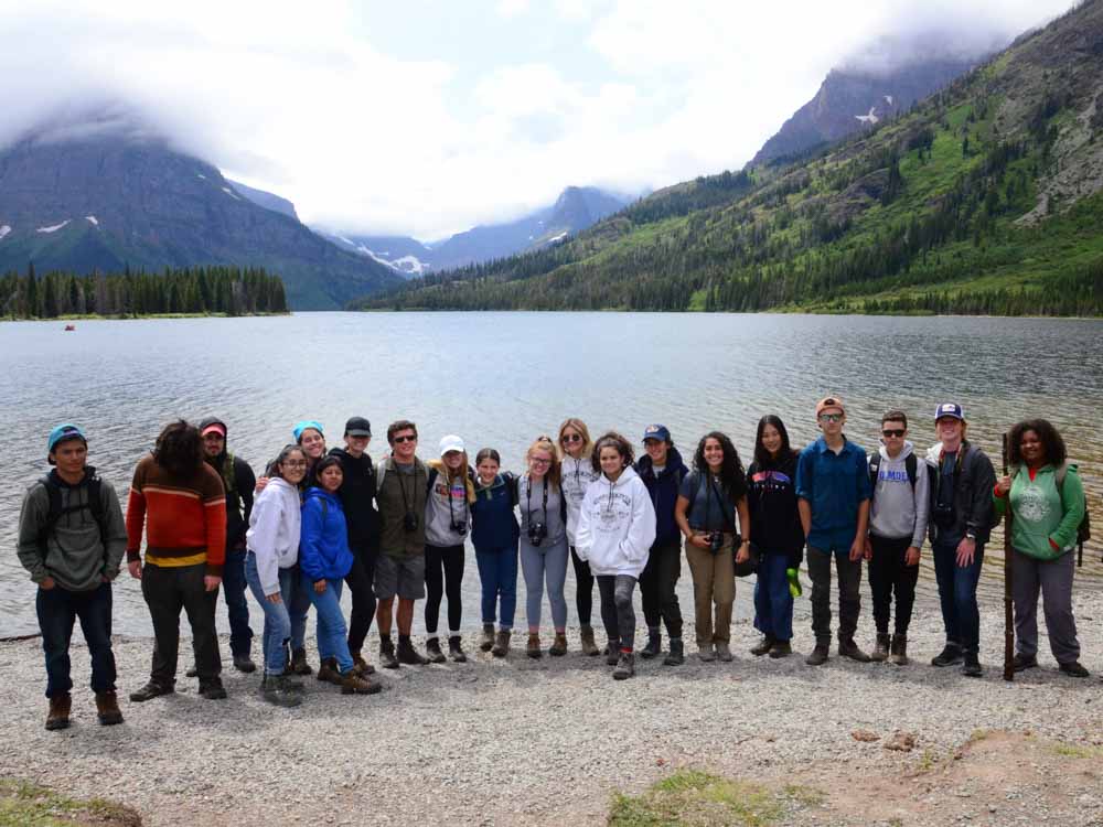A group of teen volunteers poses for a group photo at a lake in Montana.
