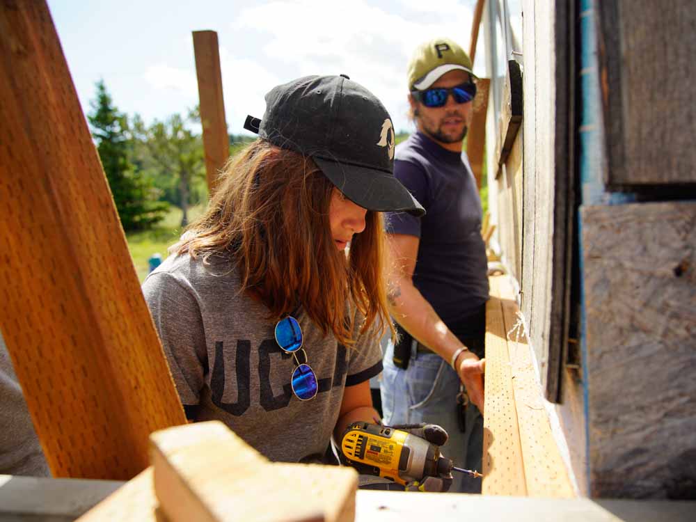 Leader and teen volunteer work to secure wood in place on their summer service project in Montana.