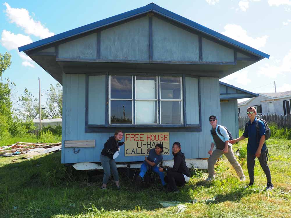 Teen volunteers pose with a house that was part of their summer service projects.