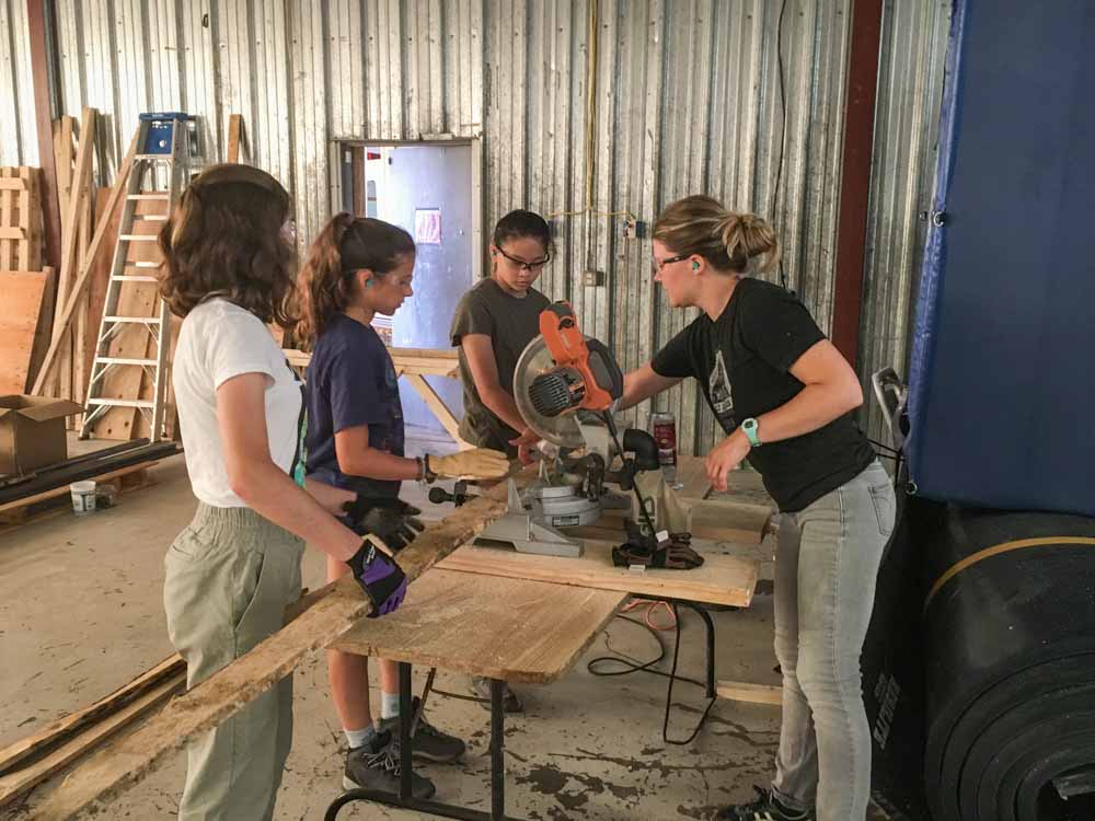 Volunteers learn to use power tools on the work site of their teen service project in Montana.