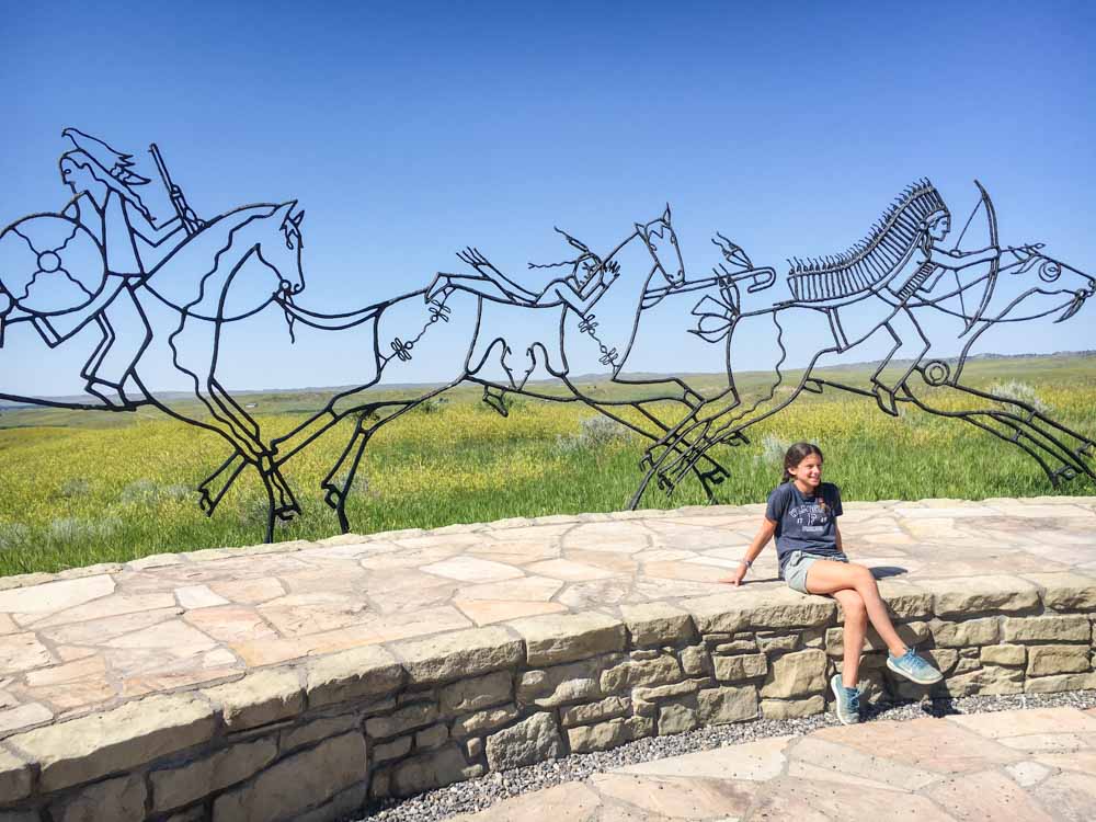 Teen volunteer sitting at Battle of Little Bighorn metal sculpture.