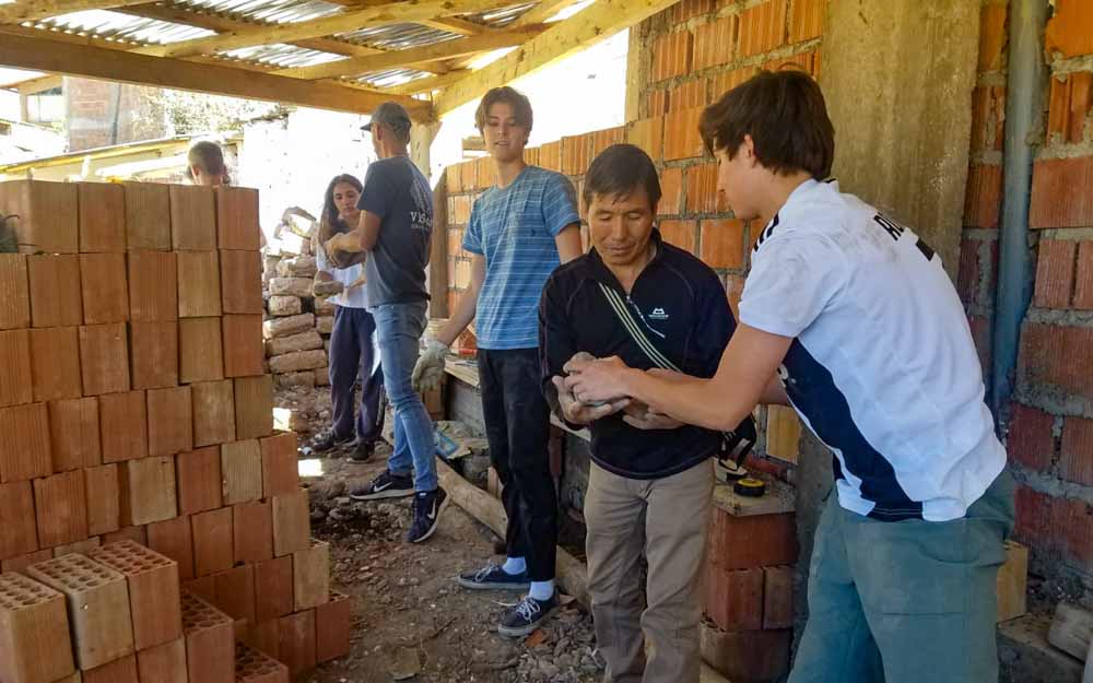 Group of volunteers passing bricks while constructing a school on a Peru summer service trip.