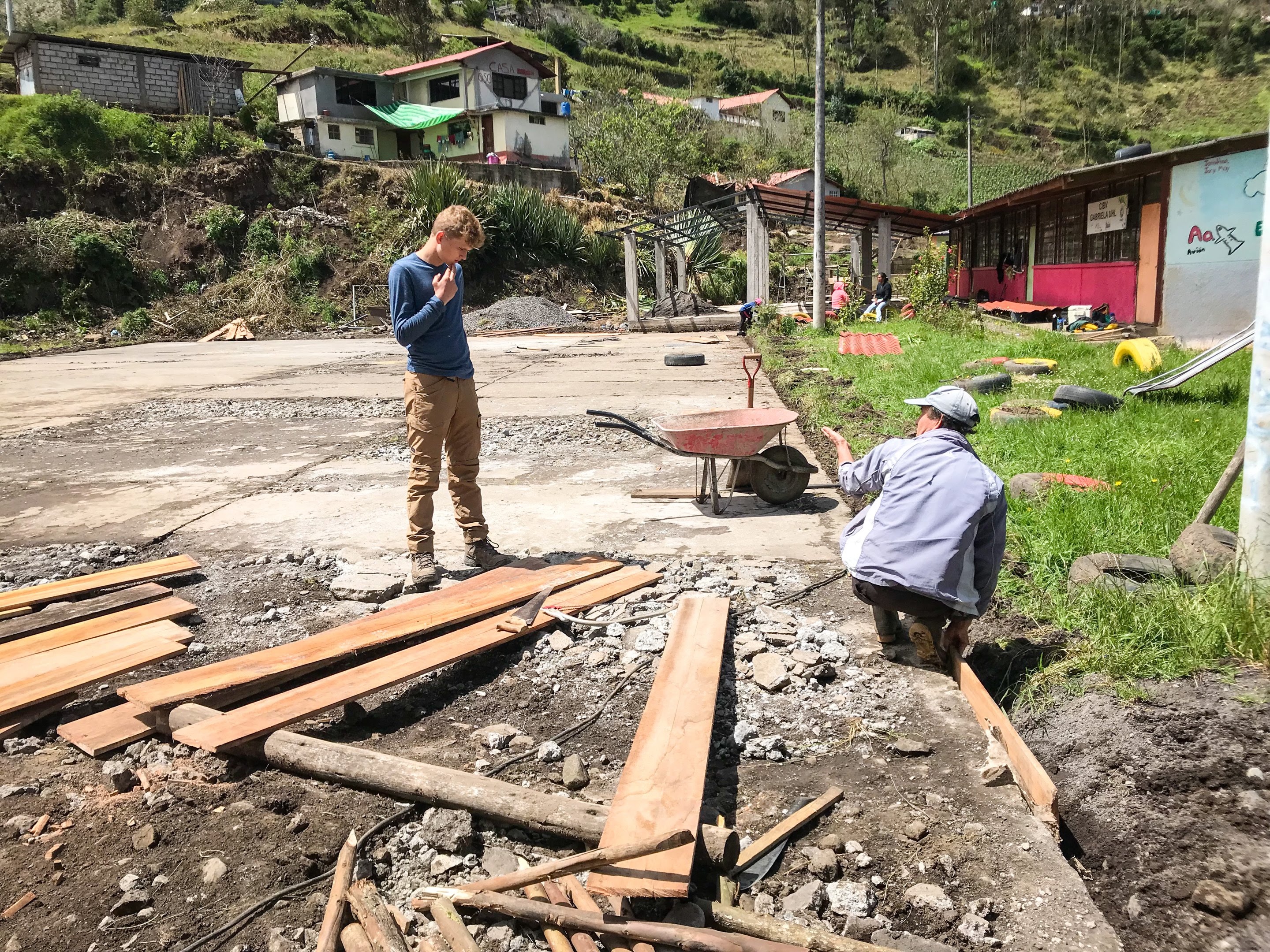 Teen volunteers helps local volunteer frame in concrete for community service project in Ecuador