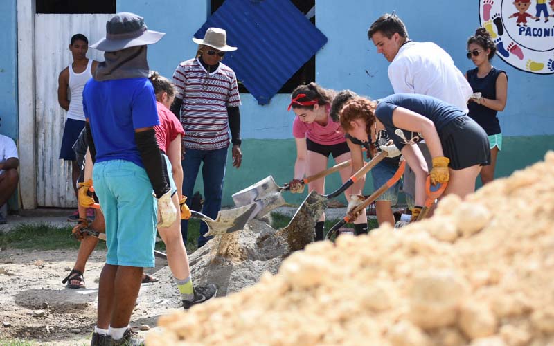 International teen volunteers work on a summer community service project by shoveling dirt for school in the Dominican Republic