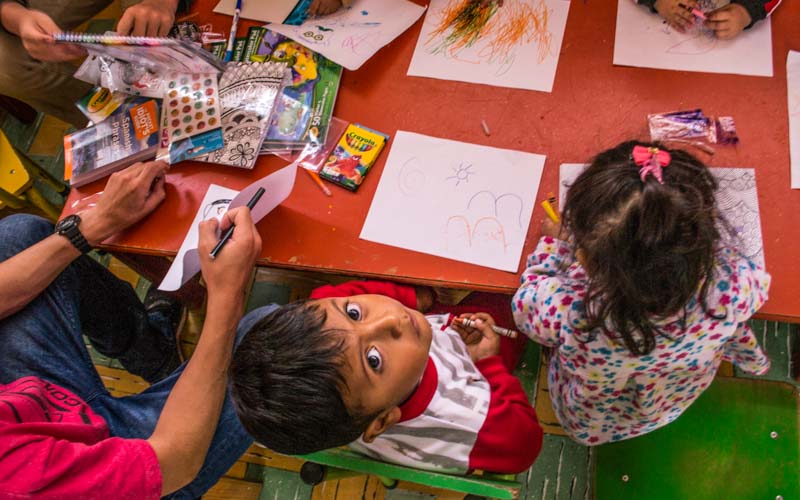 School child looks up from arts and crafts table in Ecuador