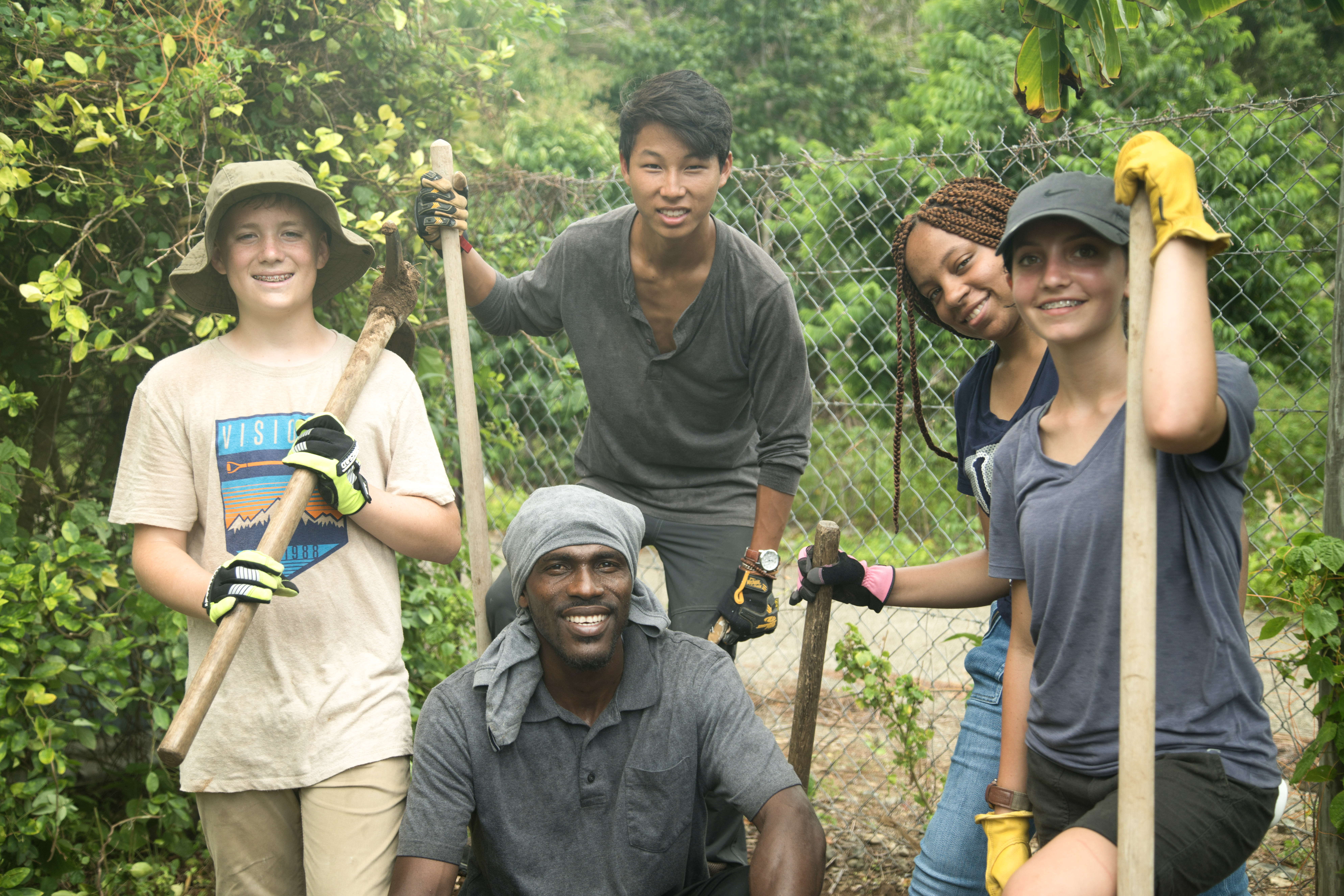 VISIONS teen volunteers and BVI community member pause working for a photo in the garden