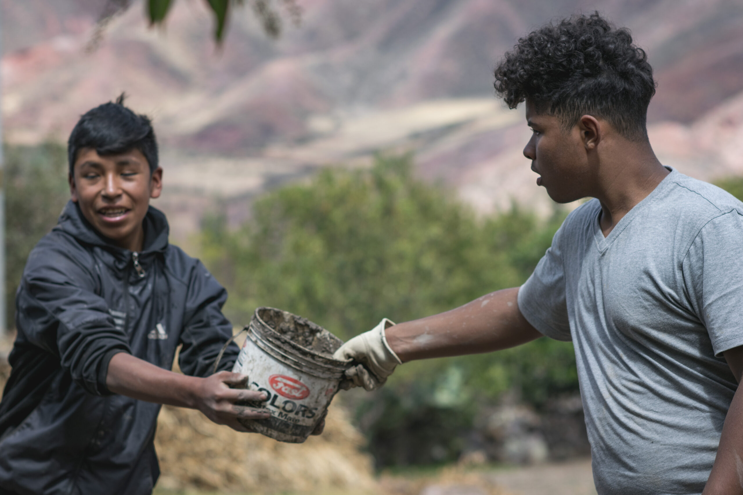 Teen volunteers in Peru pass cement to each other while working on irrigation