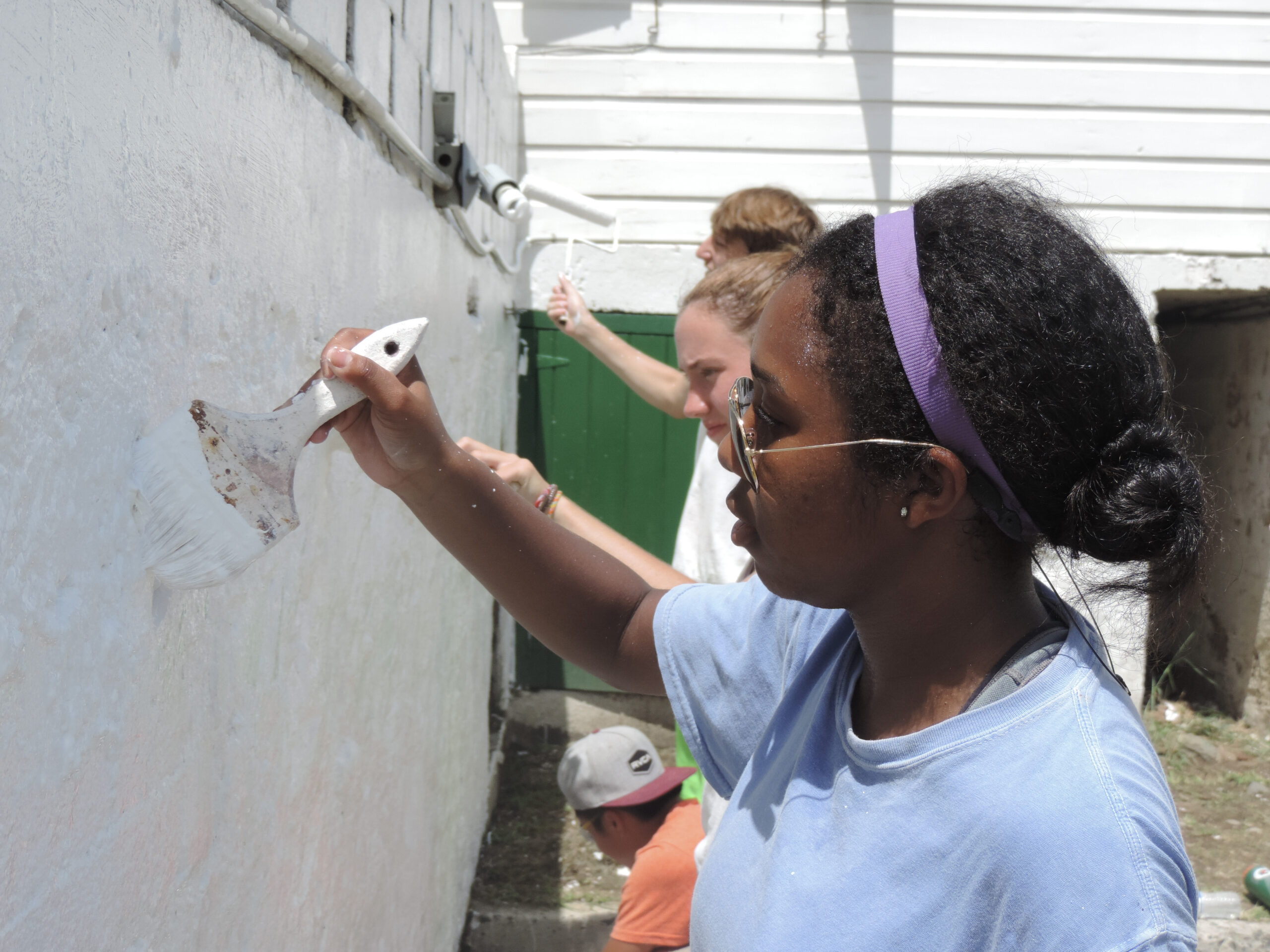 Teen girls paint a building as part of a service project