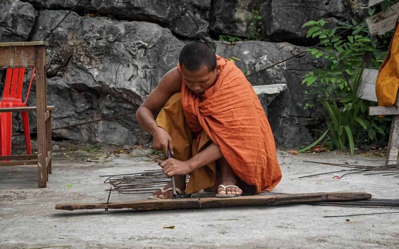 cambodian man in orange toga doing construction