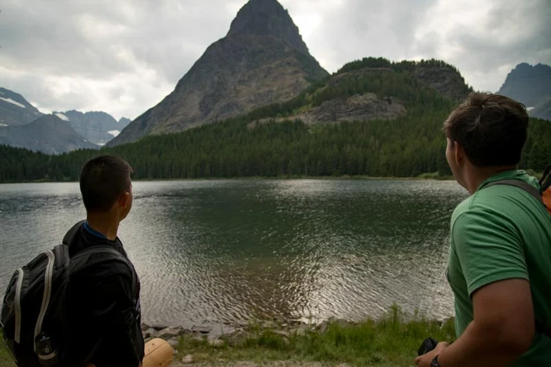 boys looking at mountain over lake