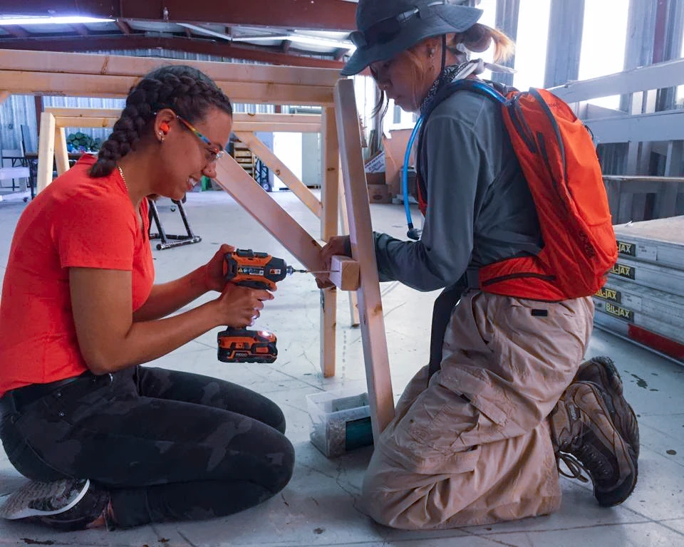 Two girls use screw gun to finish building a saw horse on community service trips to the Northern Cheyenne