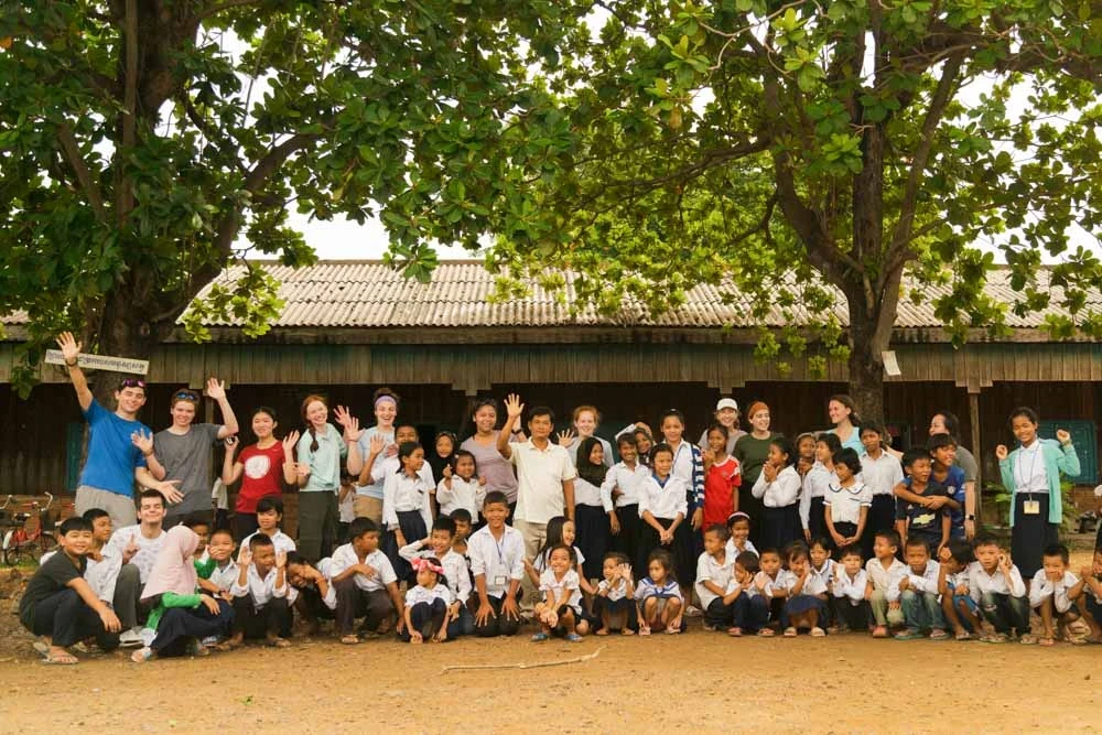Teen volunteers stand outside the school in Cambodia where they worked during their summer service trip.