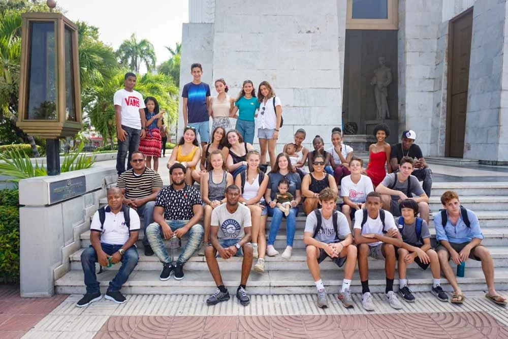 Teen volunteers and program leaders pose on some steps for a group photo in the Dominican Republic.