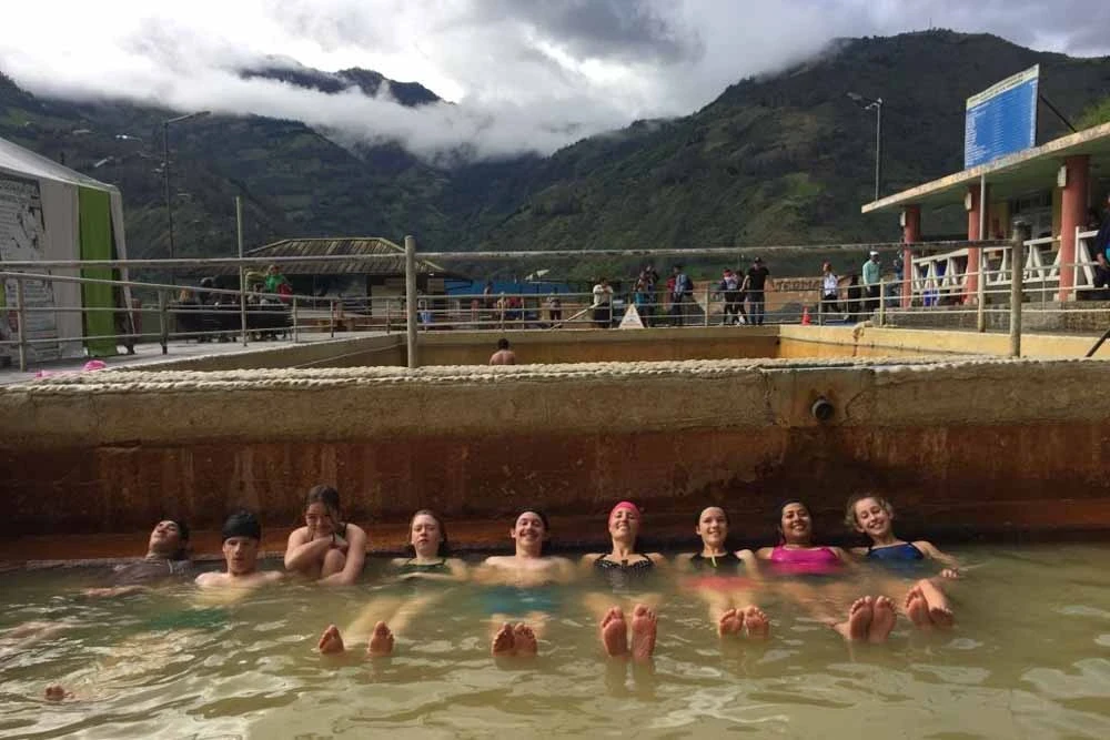 Group of teen volunteers soak at a hot spring in Ecuador during their summer travel program.