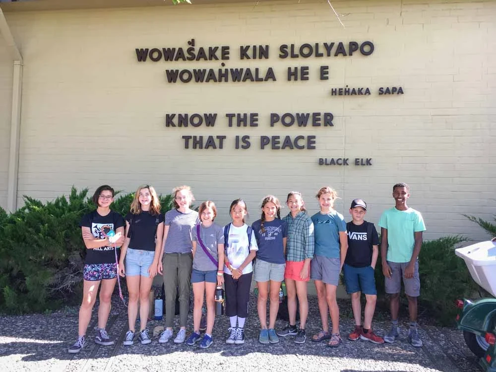 Middle school students pose next to a Native American quote.
