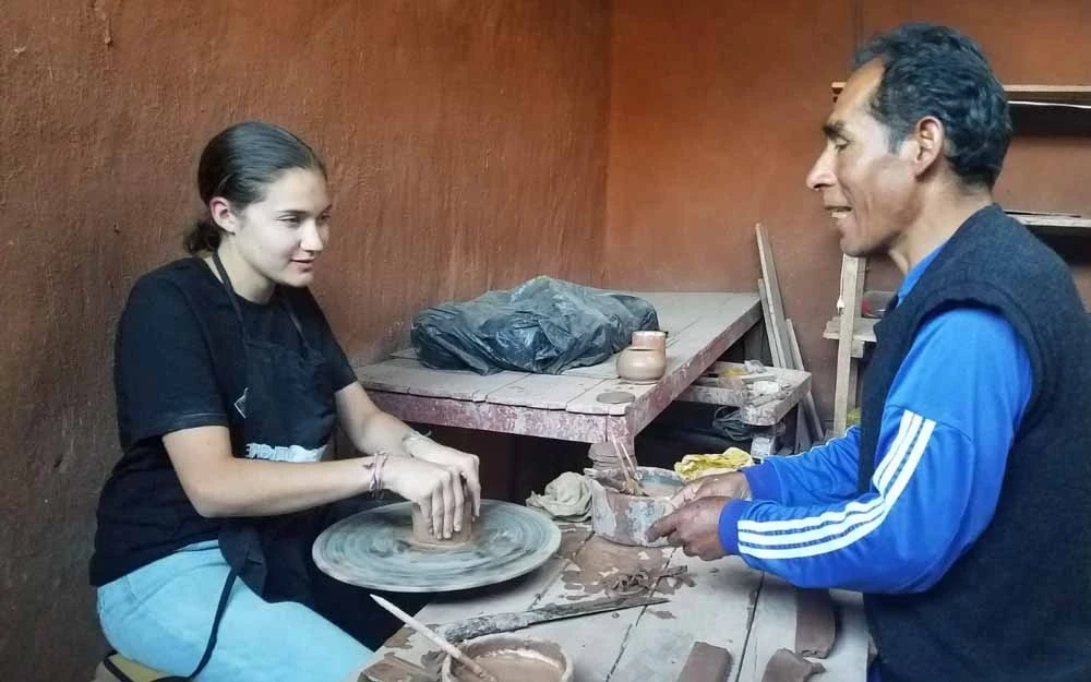 Student practicing ceramics as instructor demonstrates in Peru.