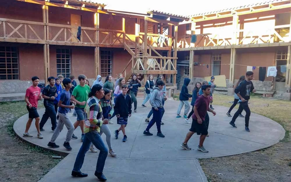 Group of students dancing on an outdoor patio during down time on their teen summer service trip.