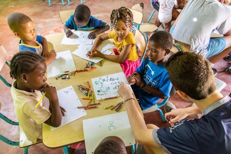 Teen volunteer works with kids in a school room in the DR