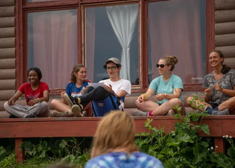 Teen volunteers give a presentation on porch of their home away from home