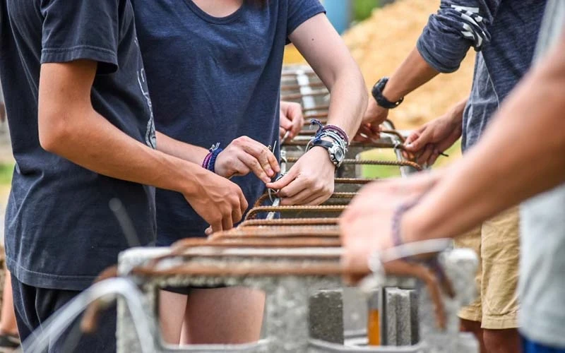 Close up of hands of an international teen service program tie rebar together in the construction of a wall in the Dominican Republic