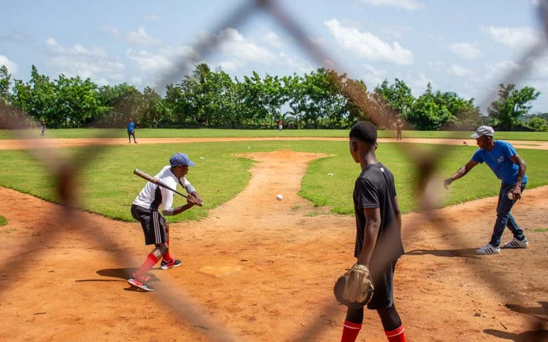 Looking through chain link fence at a baseball game in the Dominican Republic.