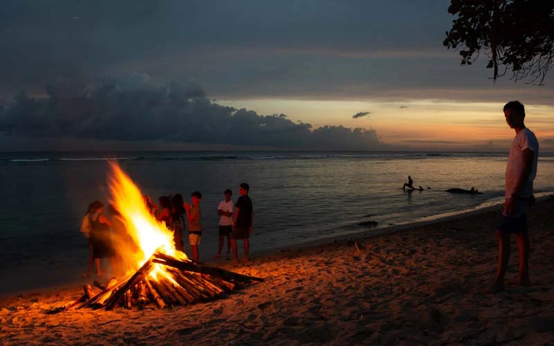 Teen volunteers stand around bonfire on beach in the Dominican Republic.