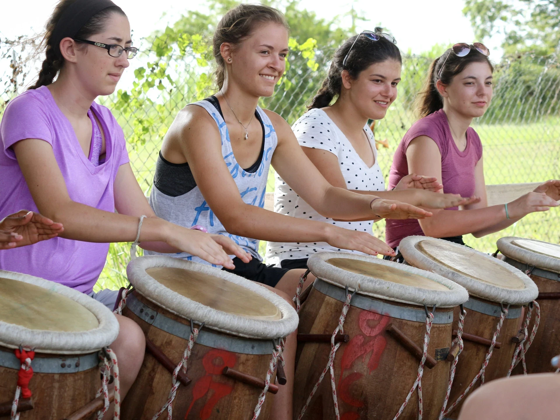 Teen girls from a VISIONS program in the Caribbean practice drumming