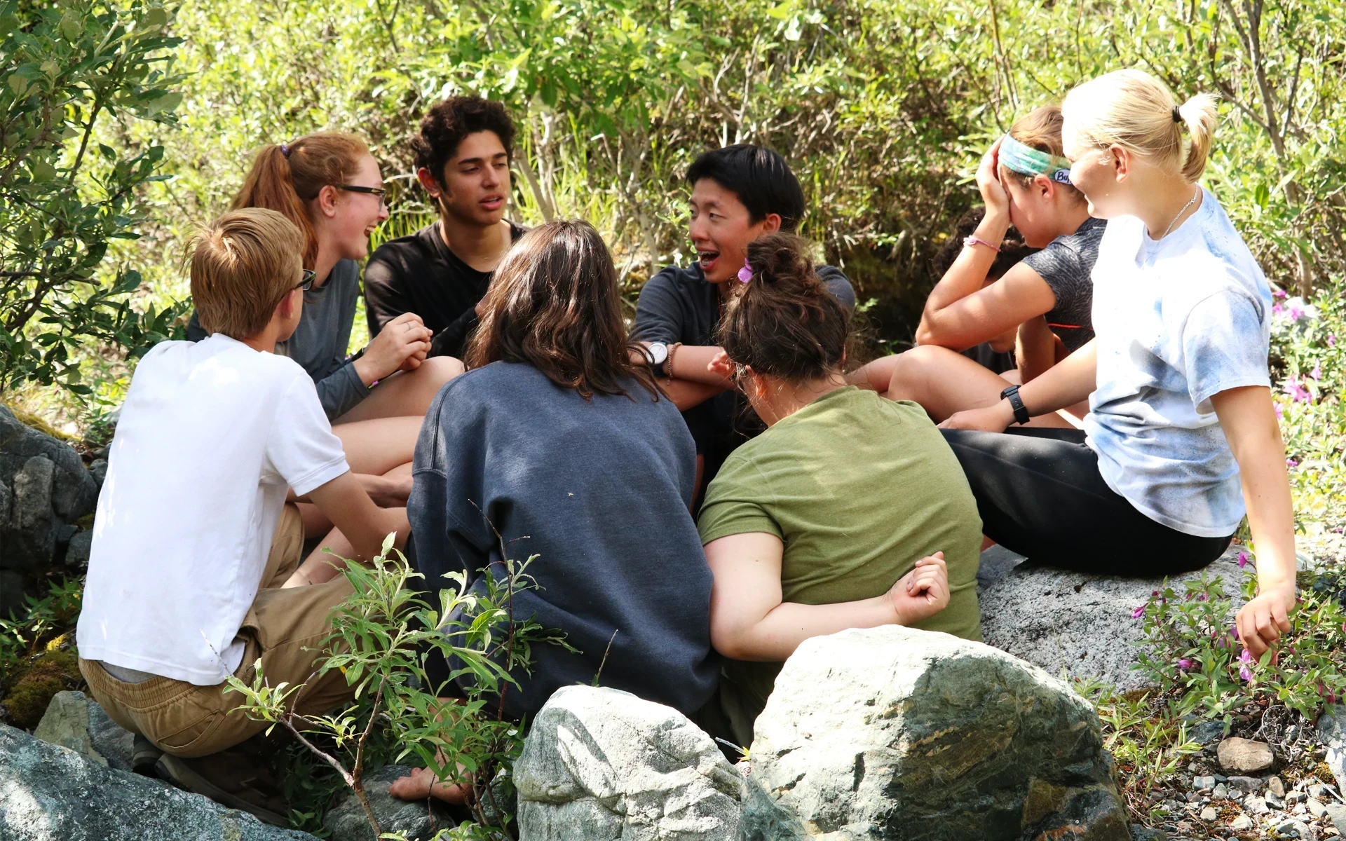 Teens share stories in a circle during a camping trip