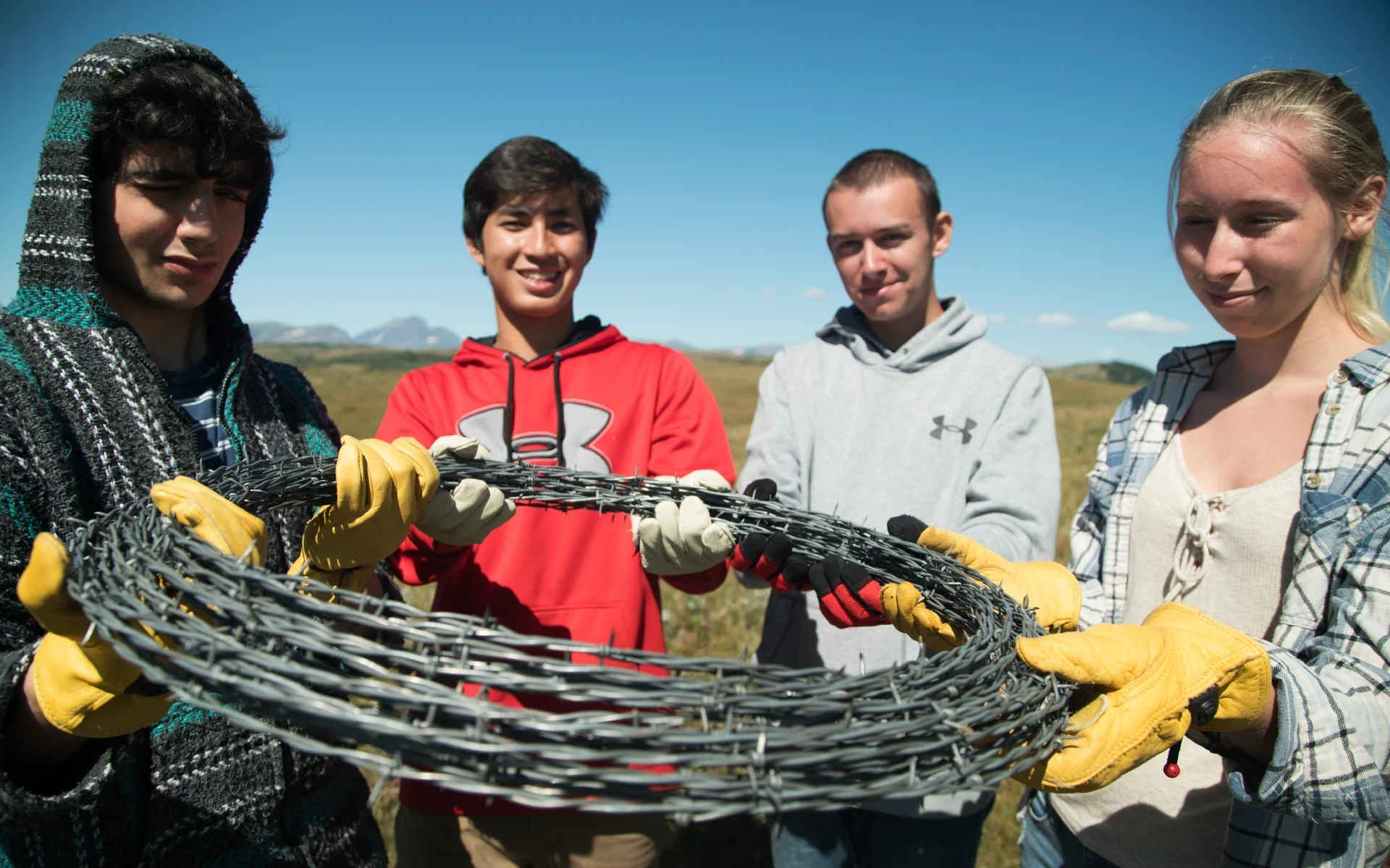teen volunteers in Montana Blackfeet hold barbed wire fencing before installing on the ranch
