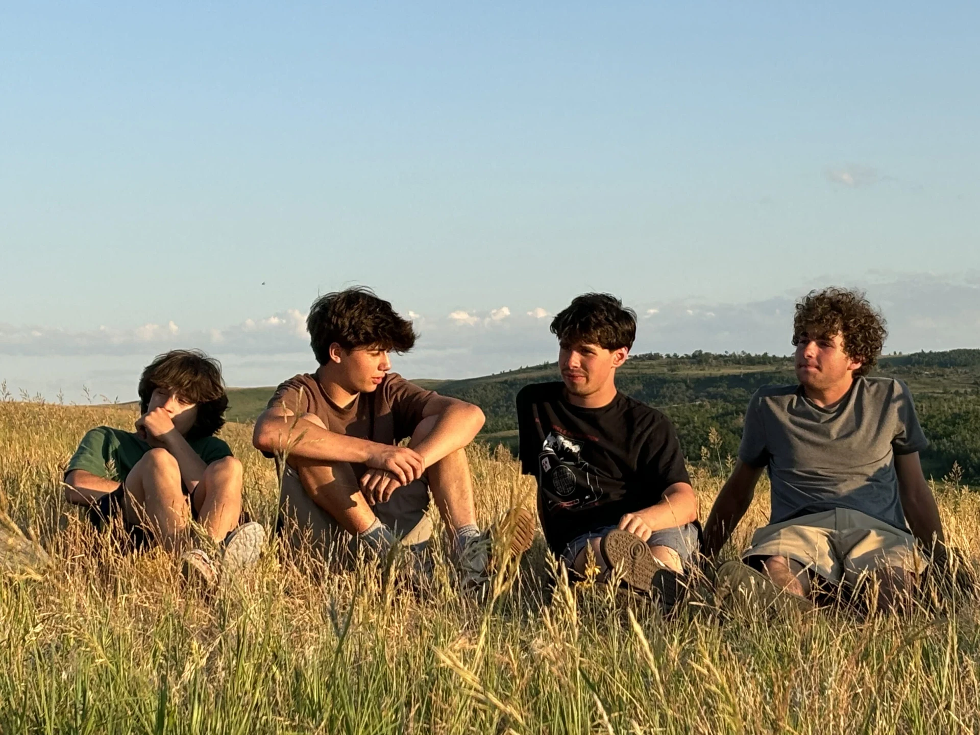 Teen boys gather in a field in Montana at sunset