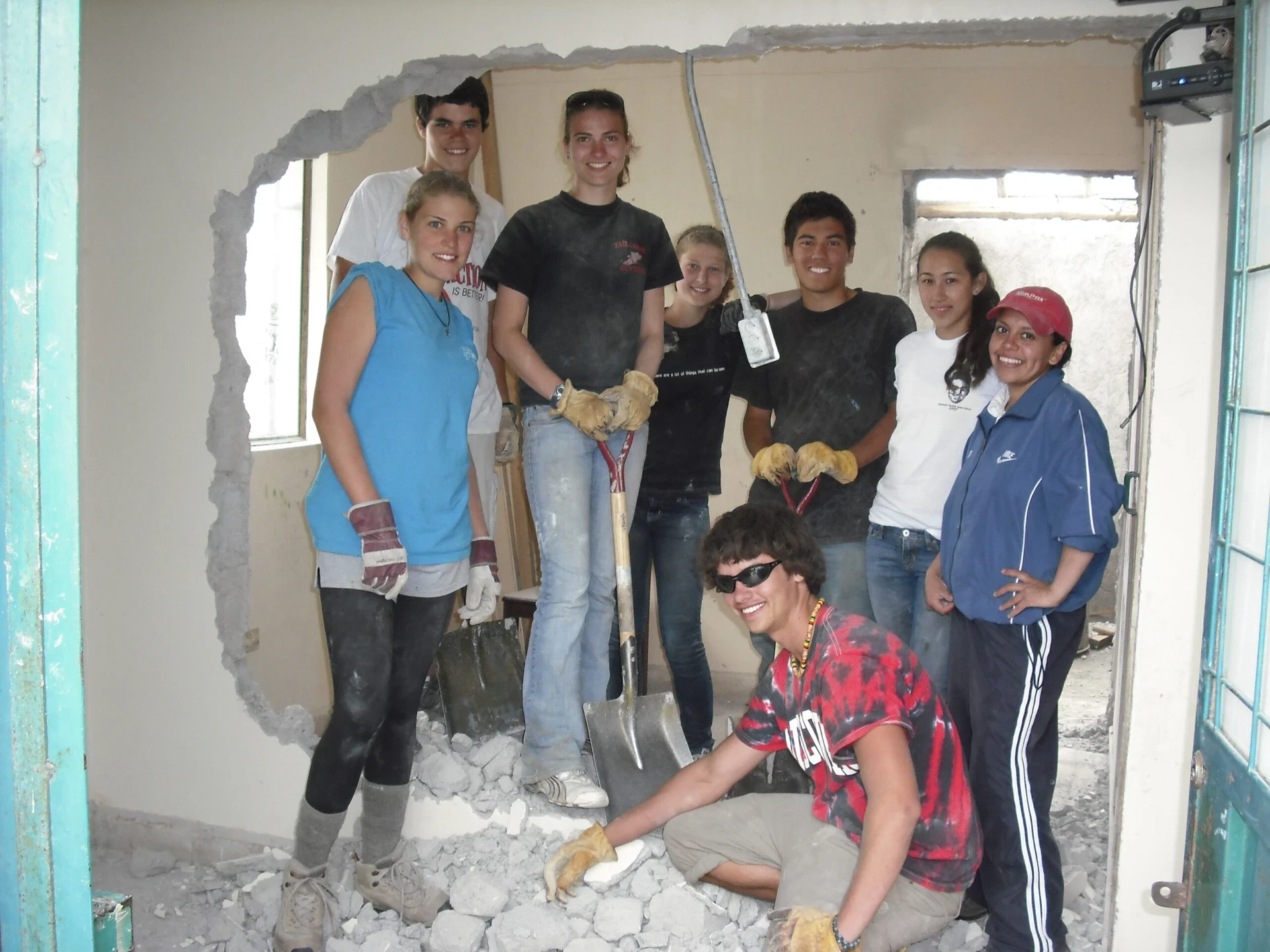 VISIONS teen and local volunteers pose after demolishing a wall for a remodel