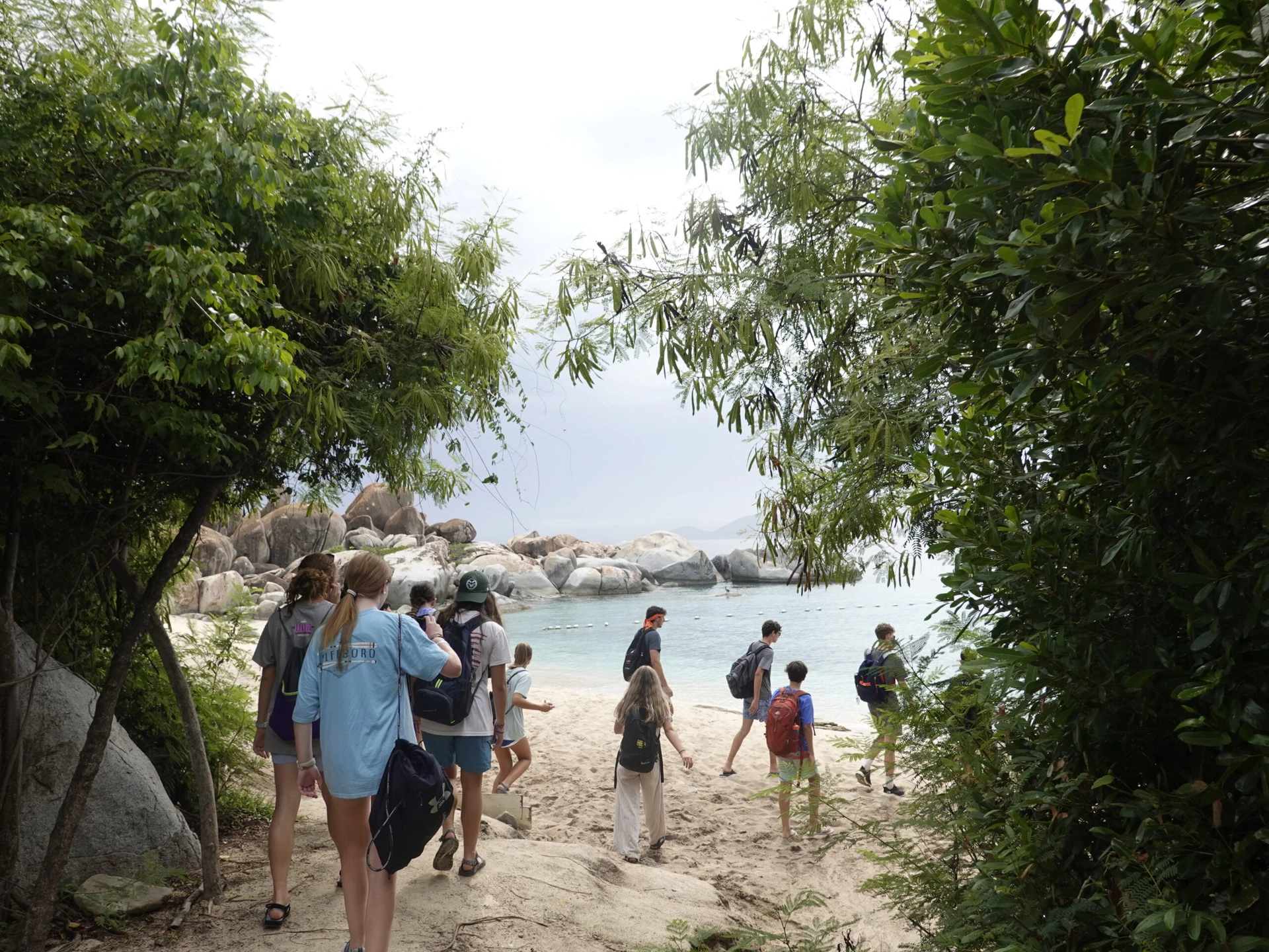 Teens walk from the trees onto a beach in the BVI